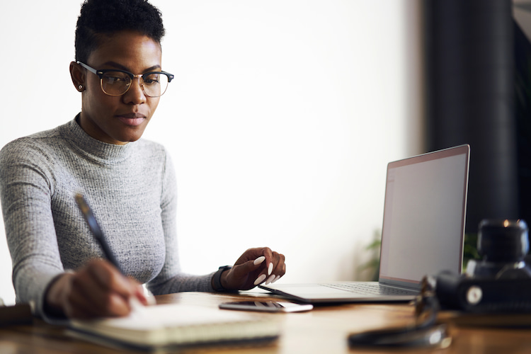 A professional researcher jotting down data points at a workdesk.